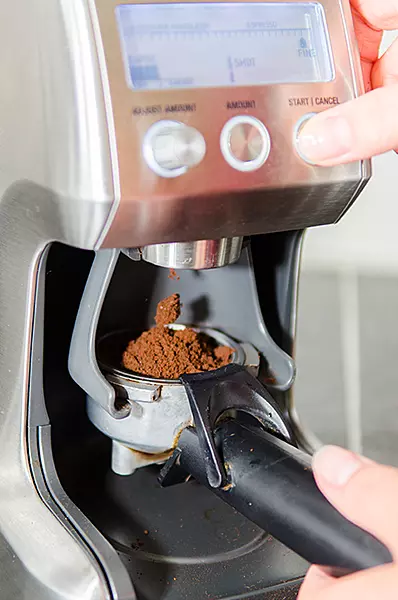 A red coffee machine with ground coffee being inserted